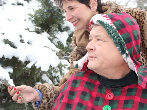 A wheelchair user enjoying a snowy day while wearing a Bailey Bug coat with a caregiver nearby